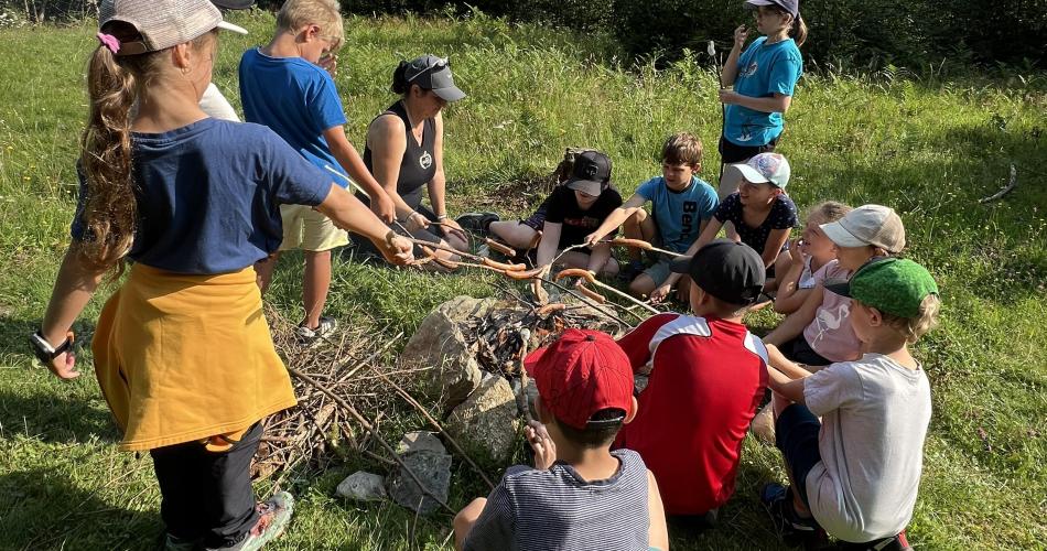Kinder beim Würstel grillen im Wald